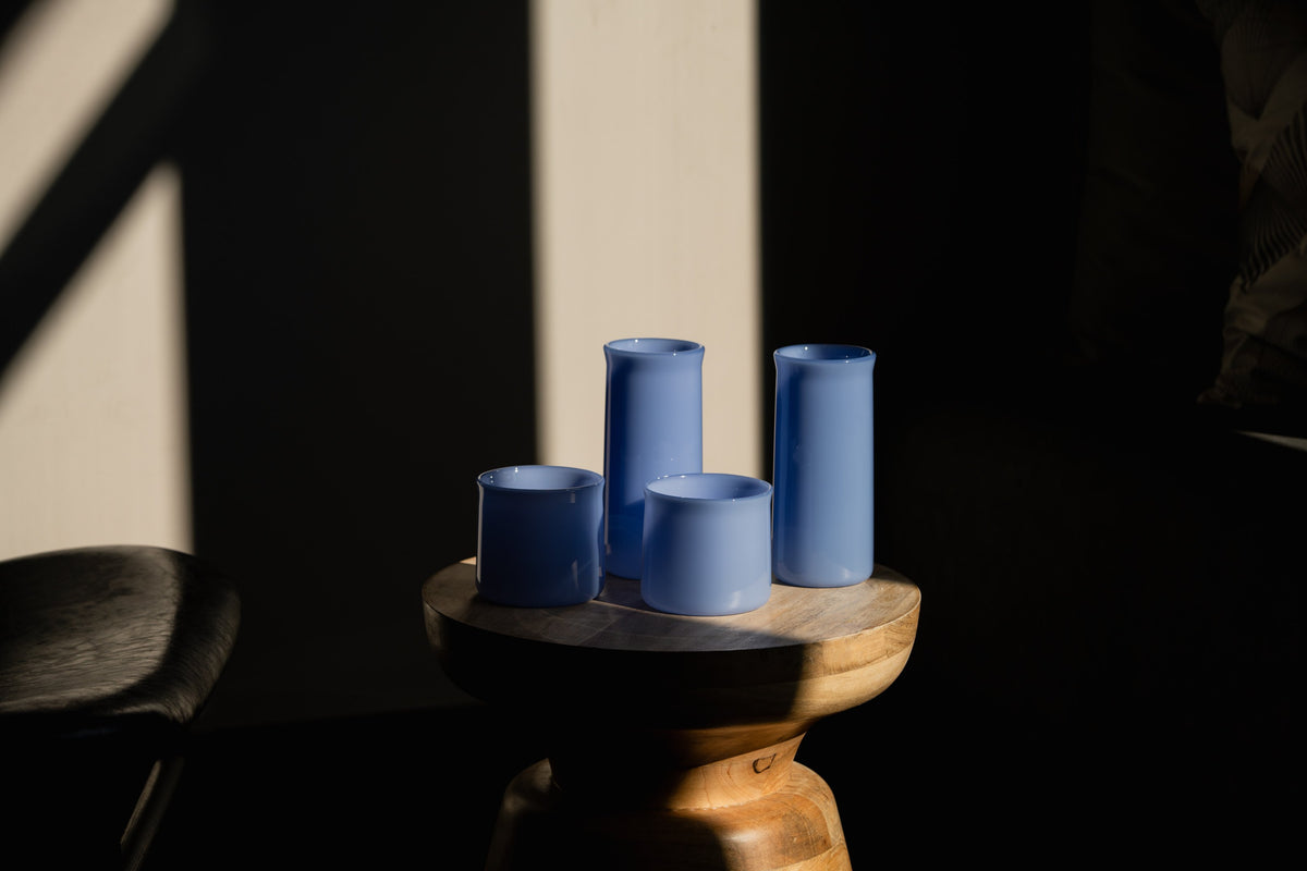 Periwinkle FLUR glasses on a wooden stool in afternoon light